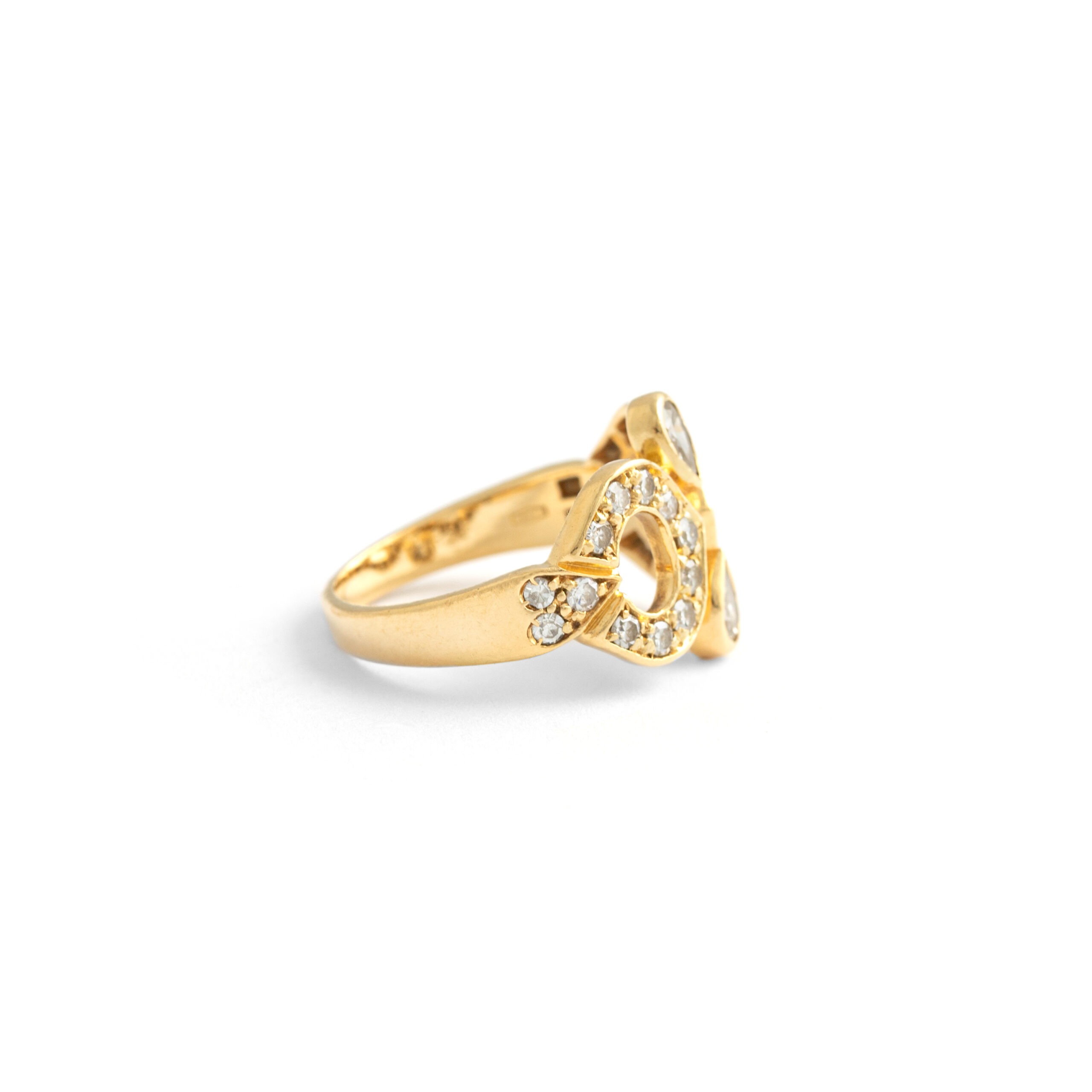 Side view of a Cartier ring in yellow gold, the pattern is in the shape of a horizontal eight and is adorned with 24 round diamonds. Two pear shaped diamonds are in the center of the ring and point towards each other