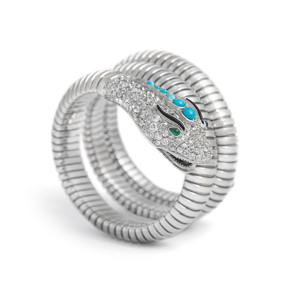 Side view of a platinum and white gold Snake Tubogaz bracelet. On the head there are 6 different sized turquoise arranged in order of size. The eyes are made of two emeralds and the eyebrows are made of onyx. The entire head is set with diamonds.
