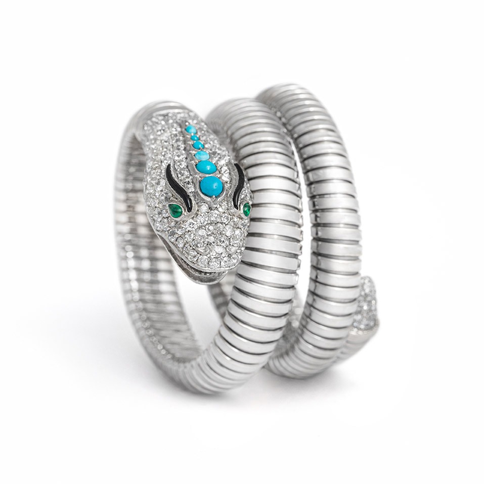 Front view of a platinum and white gold Snake Tubogaz bracelet. On the head there are 6 different sized turquoise arranged in order of size. The eyes are made of two emeralds and the eyebrows are made of onyx. The entire head is set with diamonds.