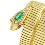 Close-up of the snake head of the bracelet. On the head is a large pear-shaped emerald surrounded by diamonds. The eyes are made of two rubies and the nose is made of a diamond. The bracelet is yellow gold