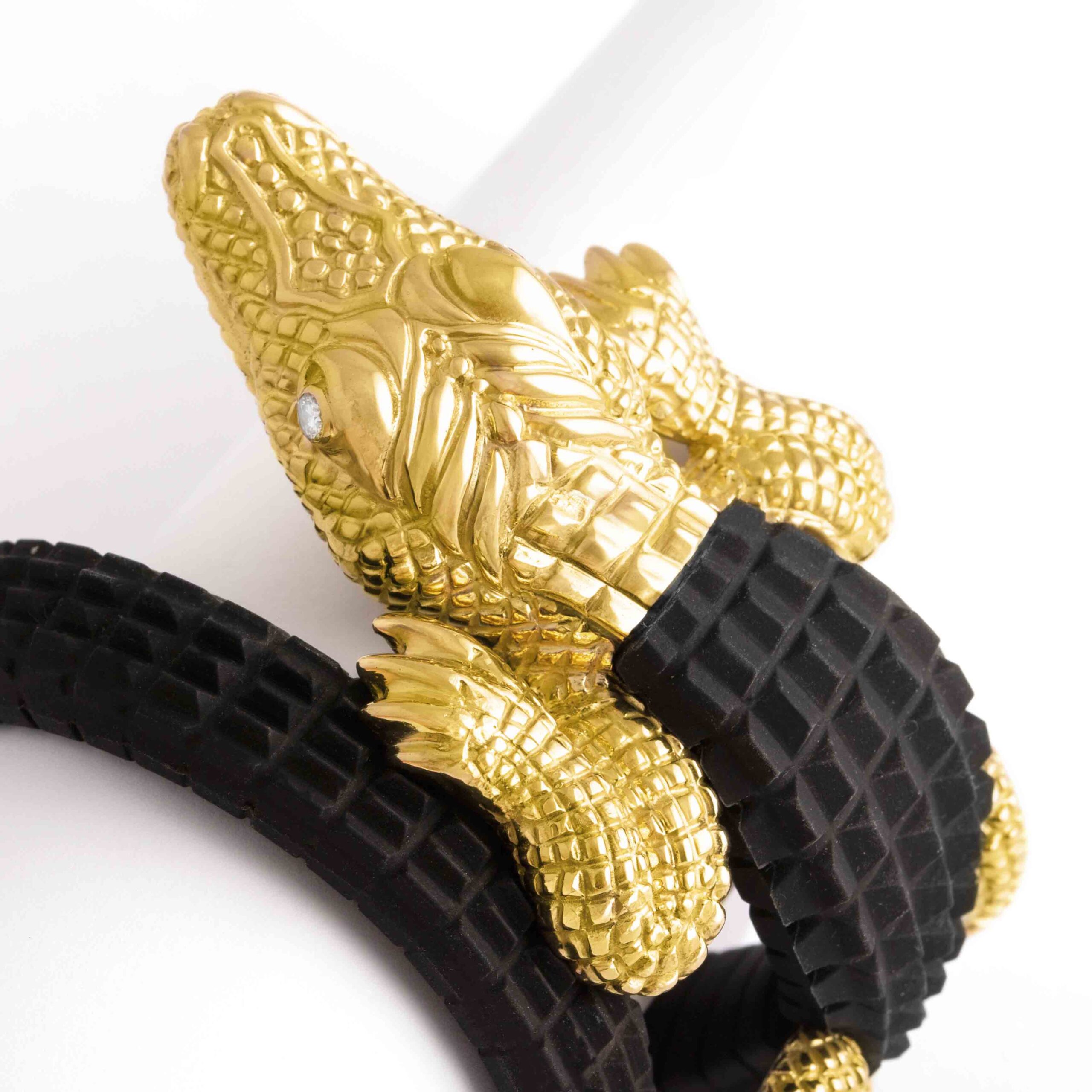 You will want to wrap this artfully sculpted creature around your wrist. Big, bold, and realistically rendered in 18K yellow gold and black rubber, this remarkable reptile has a satiny finish with shimmering highlights. The eyes are set with diamonds. The head and the feet only are in yellow gold 18K. The black rubber is brand new. It is easily removable from the spring inside so as to be changed in different colors. The overall bracelet is flexible. Unique piece